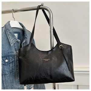 Detail of black tote bag with gold lettering 'FASHION & BAGS LEATHER' and thin straps