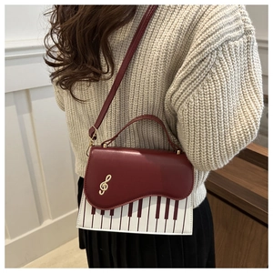 Detail of vintage square crossbody bag featuring piano key patterns and gold G-clef buckle