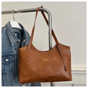 Detail of caramel faux leather tote bag showing textured surface and golden logo