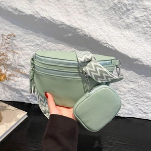 Mint green crossbody bag with wide strap and small pouch on white rock background