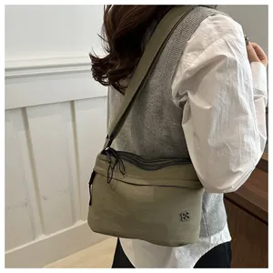 Detail of olive green nylon crossbody bag with silver clover logo and wide strap