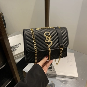 Chic black quilted crossbody bag with golden S logo and tassel in a luxury setting