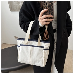 Detail of off-white corduroy tote bag with navy blue straps and side pockets