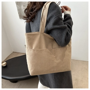 Detail of beige corduroy tote bag showing side pocket and soft texture on shoulder