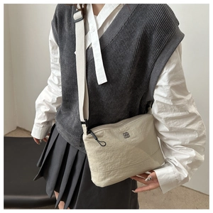 Detail of adjustable shoulder strap and metal logo on the beige nylon crossbody bag