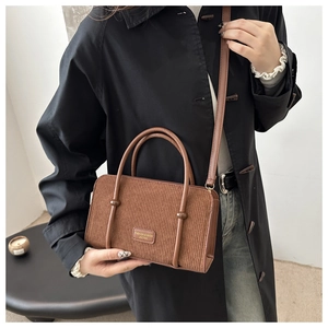 Close-up of brown corduroy handbag with metal buckle and leather label on model
