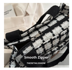 Detail of smooth metal zipper and houndstooth texture on a large checkered tote bag
