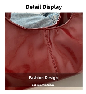 Macro shot of glossy red faux leather shoulder bag with detailed stitching on denim