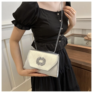 Detail of silver crossbody bag with a crystal buckle and sleek metallic finish