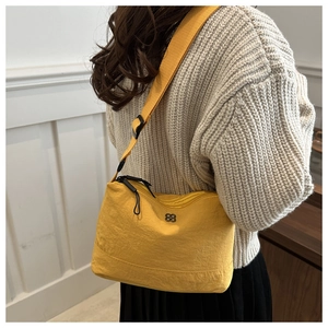 Close-up of bright yellow nylon shoulder bag with dual zippers and adjustable strap