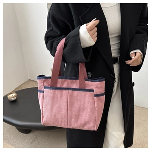 Detail of pink corduroy tote bag featuring blue contrast piping and front utility pockets