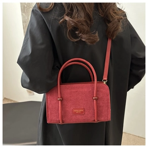 Detail of red corduroy handbag showing soft ribbed texture and fashion leather patch