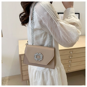 Detail of elegant chain shoulder bag featuring a sunflower crystal buckle on beige leather