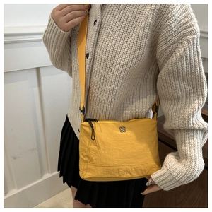 Close-up of bright yellow nylon crossbody bag with wide strap on casual outfit