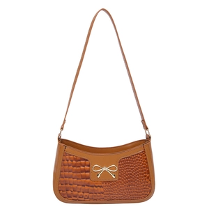 Brown crocodile embossed shoulder bag with golden bow hardware on white background