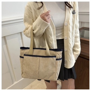 Detailed texture of corduroy tote bag with multiple pockets and contrast webbing handles