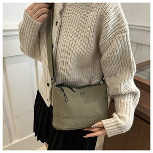 Detail of olive green nylon crossbody bag with wide shoulder strap and clover metal logo