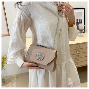 Detail of apricot chain bag featuring a large square rhinestone buckle and glossy finish