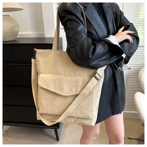 Close-up of beige corduroy tote bag showing ribbed texture and front flap pocket detail