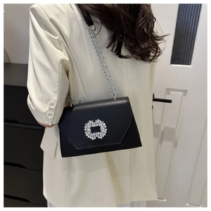 Detail of elegant black chain bag with oversized sparkling crystal buckle for evening