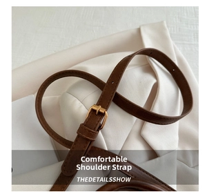 Detail of adjustable brown pebbled leather shoulder strap with gold metal buckle
