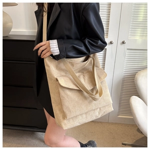 Detail view of beige corduroy tote bag showing thick ribbed texture and front flap pocket