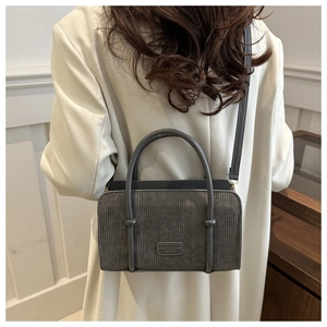 Gray corduroy crossbody bag shown on a model to demonstrate size and stylish texture