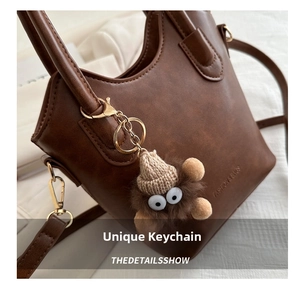 Close-up of brown PU leather bucket bag with a cute plush monster charm and gold hardware