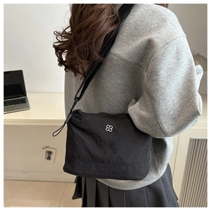 Detail of black nylon crossbody bag with silver clover logo and wide knit strap