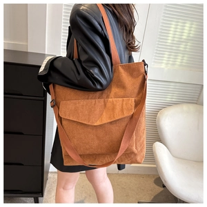 Brown corduroy tote bag showing large capacity and adjustable strap on shoulder