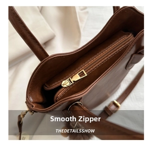 Detail view of smooth golden metal zipper and brown leather texture on bucket bag