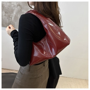 Detail of glossy deep red patent leather tote with a minimalist half-moon silhouette