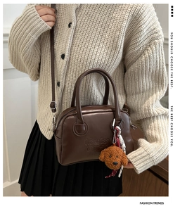 Detail of retro brown leather Boston bag with plush teddy charm and matte metal zipper