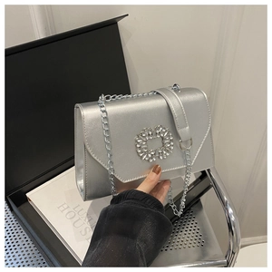 Detail of silver metallic crossbody bag with sparkling crystal buckle and chain strap