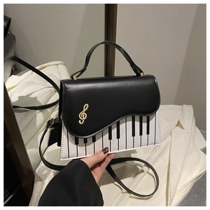 Detailed shot of the piano keyboard pattern and gold treble clef metal charm on the bag