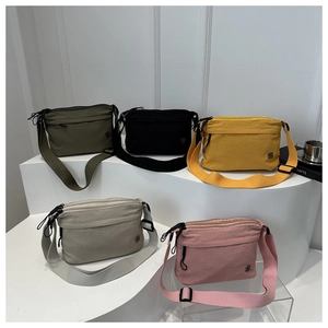 Detailed close-up of nylon crossbody bags in multiple colors with clover metal logos