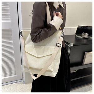 Detail of off-white corduroy tote bag showing front flap pocket and adjustable strap