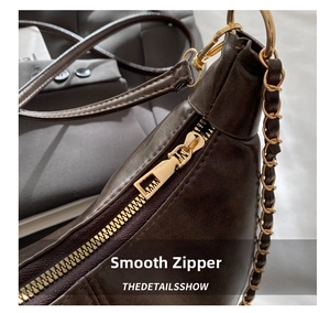 Close-up of vintage dark brown faux leather bag with premium gold zipper and metal chain
