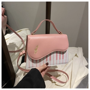 Close-up of pink piano key shoulder bag with wave edge and gold treble clef embroidery