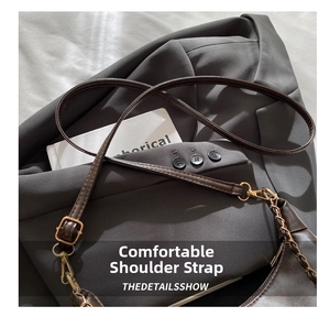 Detail of adjustable brown PU leather shoulder strap with gold metal buckle and chain hardware