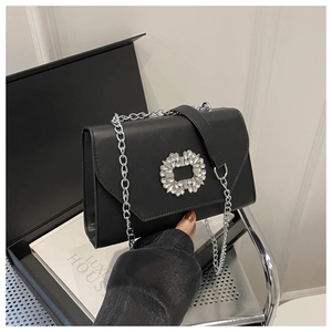 Close-up of black crossbody bag with luxury rhinestone buckle and silver chain strap