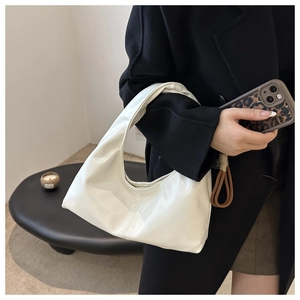 Detail of white patent leather tote bag with glossy finish and minimalist crescent design
