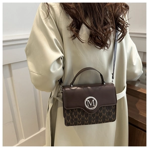 Deep brown crossbody bag with M-monogram pattern shown on model in warm lighting