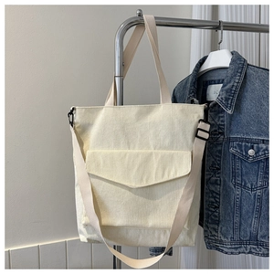 Close-up of cream corduroy tote bag with front pocket and adjustable shoulder strap
