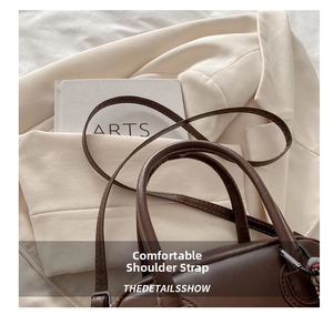 Top-down view of brown leather pillow bag with fine stitching and dual handles