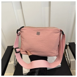 Detail of pink canvas crossbody bag with silver floral logo and wide fabric strap