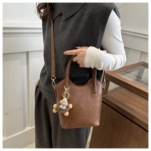 Detail of vintage brown PU leather bucket bag with plush charm and fashion embossing