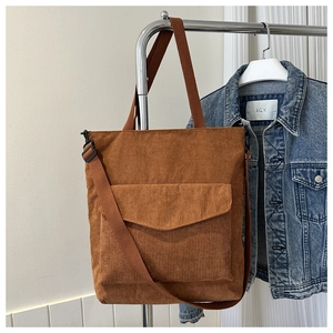 Detailed close-up of brown corduroy tote bag showing large front pocket and adjustable strap