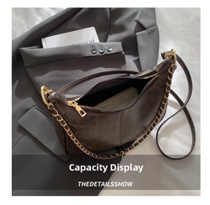 Detail view of brown crescent shoulder bag interior with a long wallet and gold chain