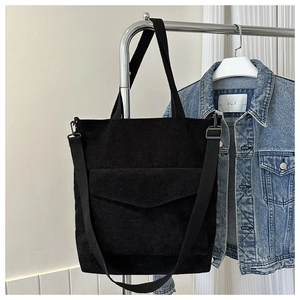 Detail of black corduroy tote bag showing front pocket and detachable shoulder strap